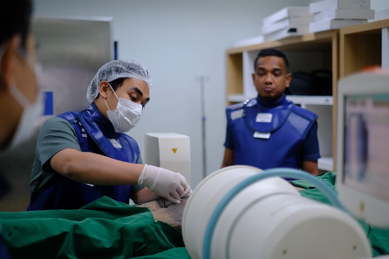 Medical staff in protective vests performing fluoroscopy-guided procedure